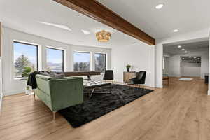 Living room featuring beamed ceiling, light wood finished floors, and recessed lighting