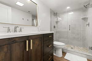Bathroom featuring vanity, a stall shower, and light wood-style flooring