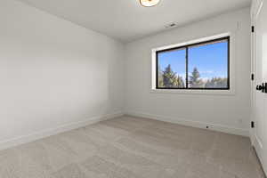 Spare room featuring light carpet and baseboards