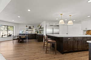 Kitchen featuring dual tone cabinets, backsplash, dark wood finished floors, decorative light fixtures, and a kitchen breakfast bar