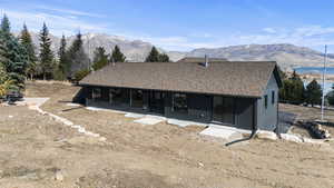 Back of house featuring a mountain view, a sunroom, and roof with shingles