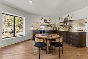Dining space with a dry bar, wine cooler, light wood-style flooring, and a textured ceiling