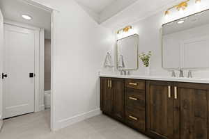 Bathroom with double vanity, recessed lighting, and light tile patterned flooring