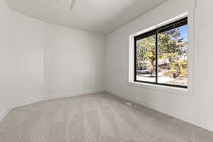 Unfurnished room featuring light carpet and baseboards