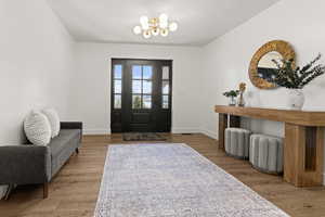 Foyer entrance with light wood-type flooring, suspended lighting, and a textured ceiling