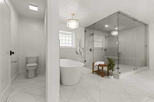 Bathroom with a shower stall, a freestanding bath, light marble finish flooring, and a chandelier