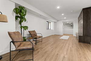Living area with light wood finished floors and recessed lighting