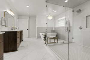 Full bathroom with vanity, a stall shower, a soaking tub, light marble finish floors, and recessed lighting