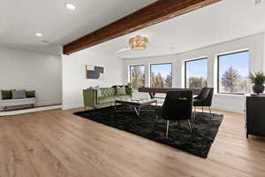Living room with light wood-style floors, beamed ceiling, and recessed lighting