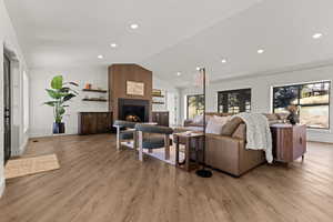 Living room with a large fireplace, light wood-type flooring, and recessed lighting