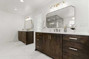 Bathroom with two vanities, light marble finish flooring, and recessed lighting