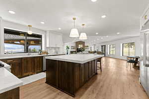 Two tone kitchen with open floor plan, a center island, a breakfast bar, plenty of natural light, and two tone cabinetry
