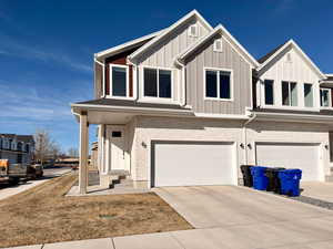 View of front of home featuring an attached garage, driveway, a porch, board and batten siding, and a front yard