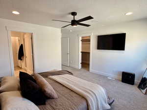 Bedroom featuring a textured ceiling, carpet, a walk in closet, recessed lighting, and ceiling fan