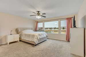 Primary bedroom featuring light colored carpet and ceiling fan