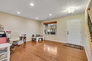 Office area with light wood-style floors, recessed lighting, and a textured ceiling