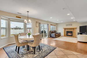 Dining space with light tile patterned floors, a chandelier, and a fireplace