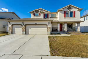 Traditional-style home featuring a front lawn, covered porch, concrete driveway, stucco siding, and a garage