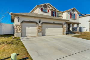 View of front facade featuring a garage, concrete driveway, roof with shingles, stone siding, and stucco siding