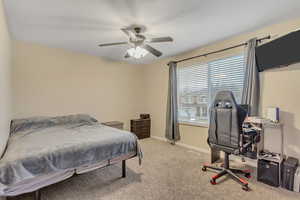 Bedroom featuring an office area, light carpet, ceiling fan, and a textured ceiling