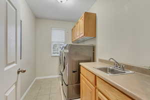 Laundry area with cabinet space, light tile patterned flooring, washer and clothes dryer, and a textured ceiling
