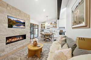 Living area featuring a fireplace, light wood-type flooring, lofted ceiling with beams, and suspended lighting