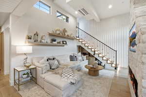Living area featuring a high ceiling, light wood-style flooring, a fireplace, and cooling unit