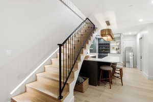 Staircase featuring wood finished floors, recessed lighting, and wet bar