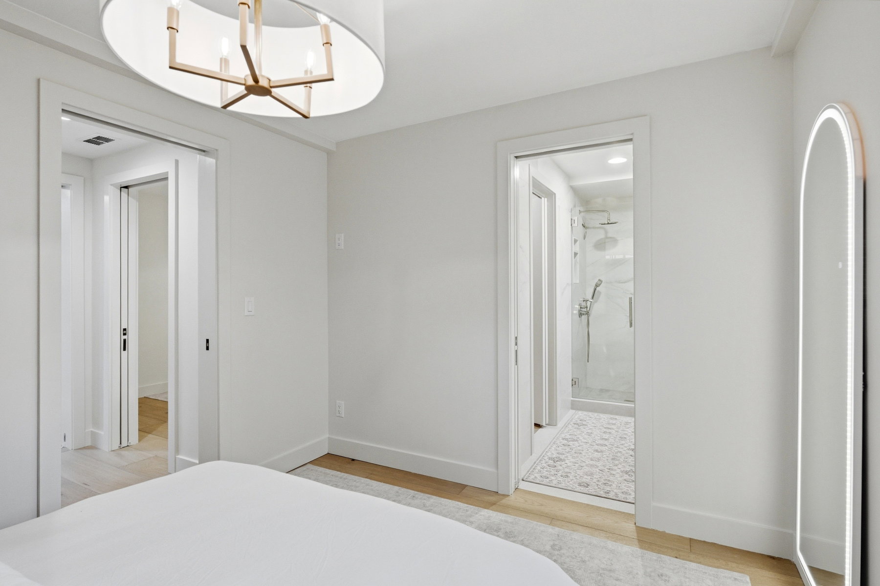 Bedroom with hanging lights, light wood-type flooring, and ensuite bath