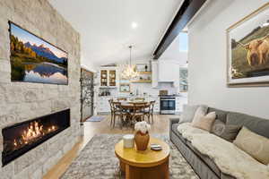 Living area featuring a fireplace, light wood-style floors, lofted ceiling, and hanging lights