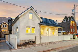 View of front of house featuring a standing seam roof, a porch, and a chimney