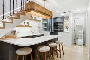 Kitchen with open shelves, a breakfast bar area, recessed lighting, a peninsula, and light wood-type flooring