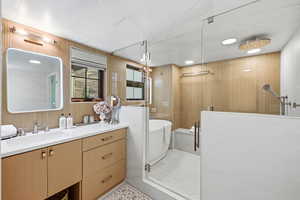 Full bath with vanity, a shower stall, wood walls, and a freestanding tub