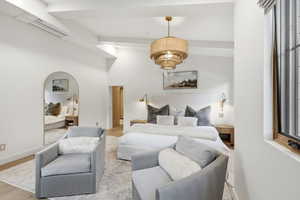 Bedroom with wood finished floors and beam ceiling