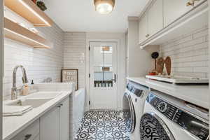 Laundry room featuring washing machine and dryer, cabinet space, and light tile patterned flooring