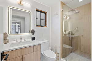 Bathroom featuring vanity, a shower stall, and tile walls