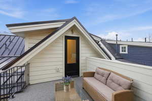 Property entrance featuring an outdoor lounge area and roof with shingles