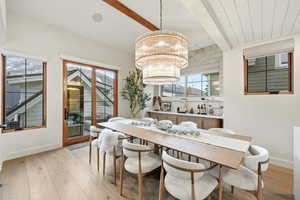Dining space featuring light wood-style floors, beam ceiling, healthy amount of natural light, and hanging lights