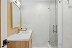 Full bath featuring vanity and a marble finish shower