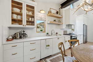 Kitchen with white cabinets, light countertops, stainless steel appliances, and light wood-style floors