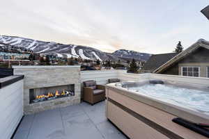 View of patio with a mountain view and a hot tub