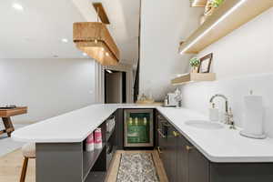 Kitchen featuring a peninsula, beverage cooler, open shelves, a breakfast bar area, and recessed lighting