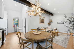 Dining room with a chandelier, light wood finished floors, and lofted ceiling