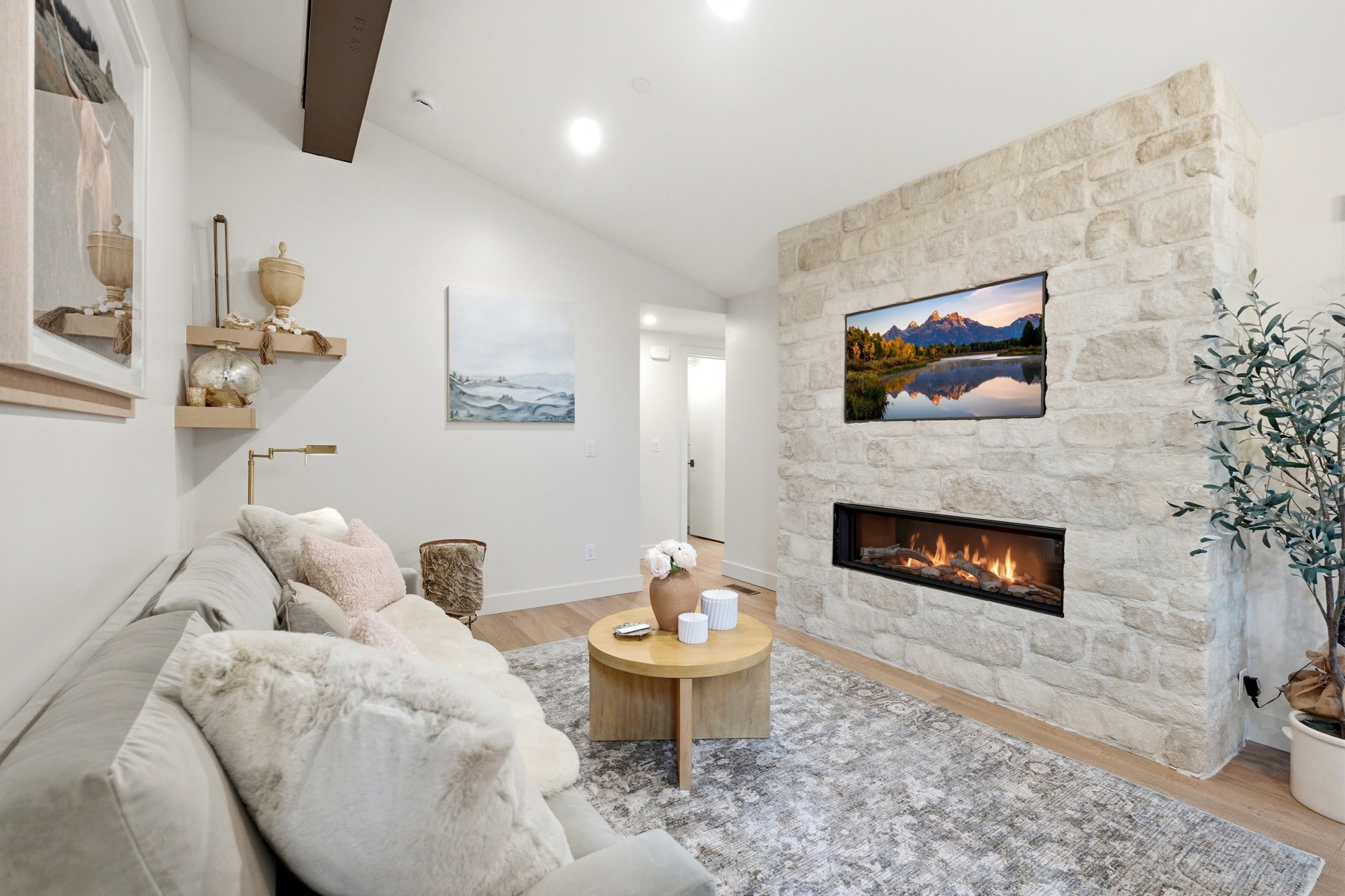 Living room with light wood-style flooring, a fireplace, and vaulted ceiling with beams