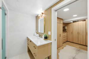 Full bath featuring light wood finished floors, vanity, and recessed lighting