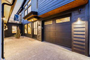 View of exterior entry with an attached garage and a patio