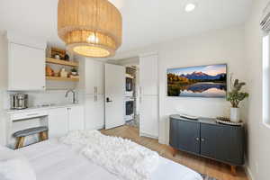 Bedroom with stacked washer / dryer, light wood finished floors, and recessed lighting