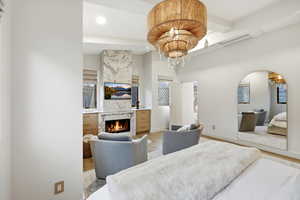 Bedroom with a chandelier, arched walkways, wood finished floors, and a fireplace