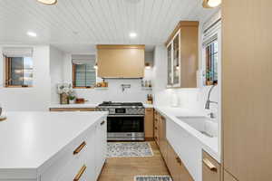 Kitchen featuring two tone color scheme, high end stove, wooden ceiling, light wood-style floors, and extractor fan