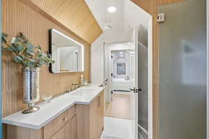 Bathroom featuring vanity, lofted ceiling, connected bathroom, and recessed lighting